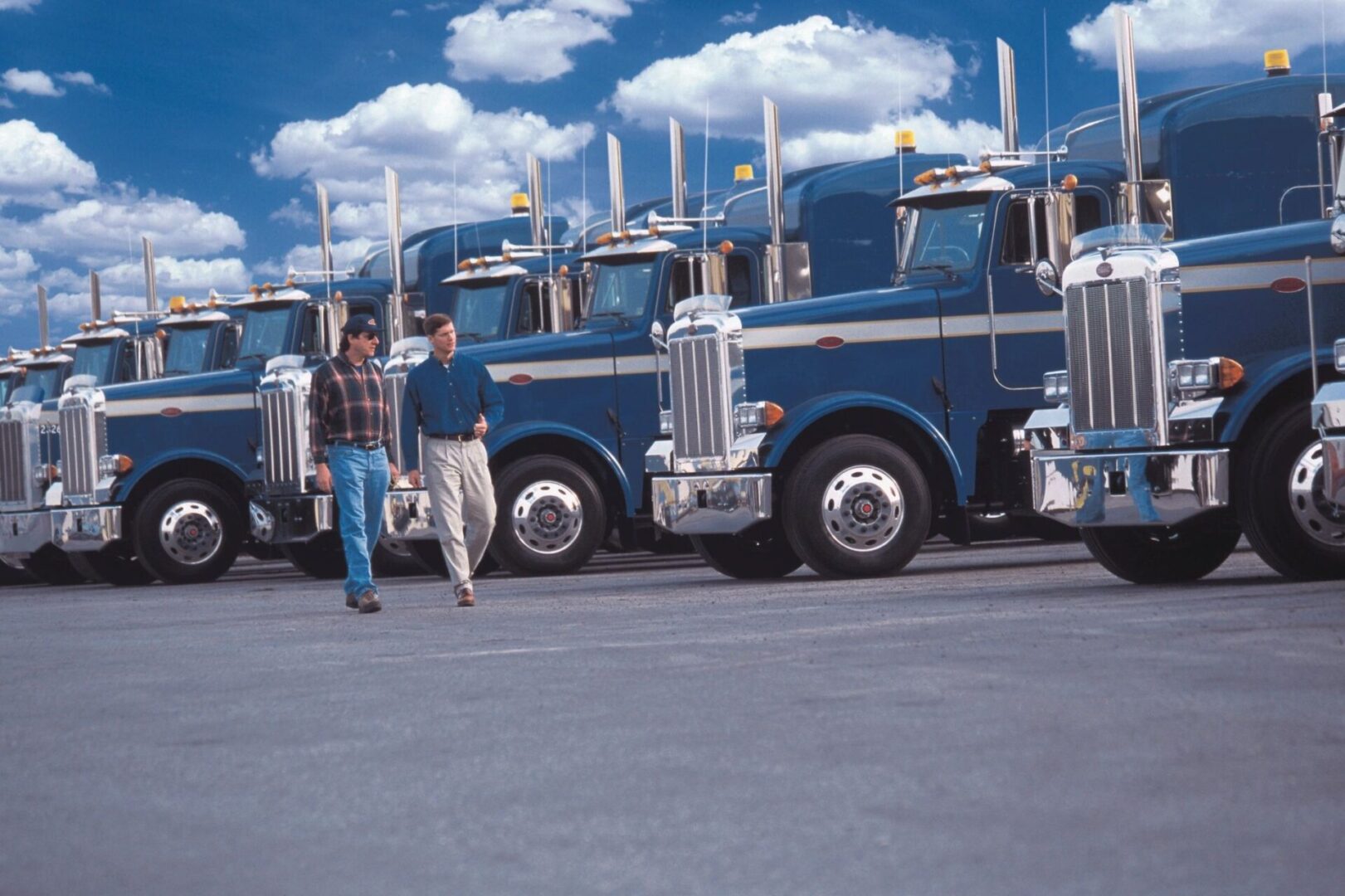 Two men walking in the parking lot of trucks